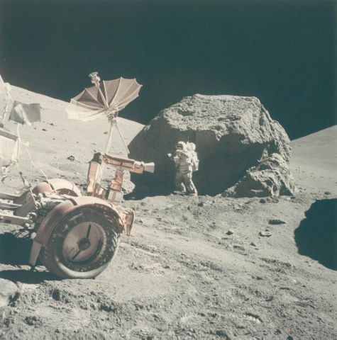 Harrison Schmitt à proximité d'un imposant rocher, le rover au…